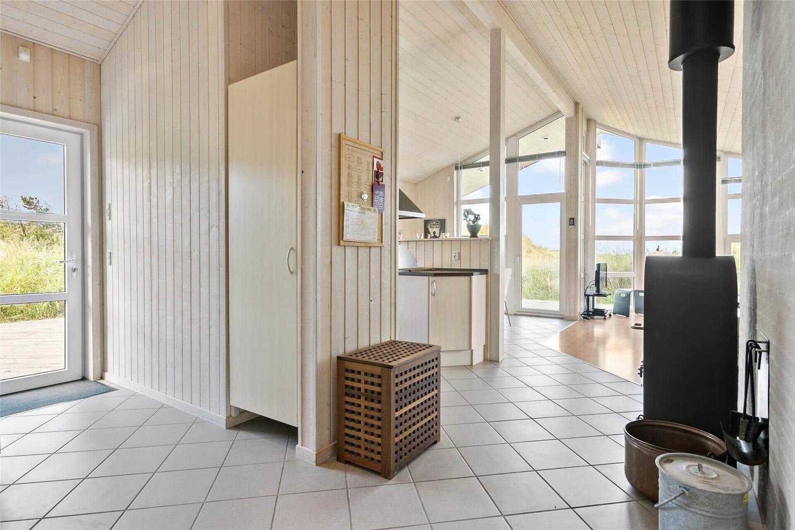 Eingangsbereich mit Holzwand, Kamin und Blick auf die Küchenzone.