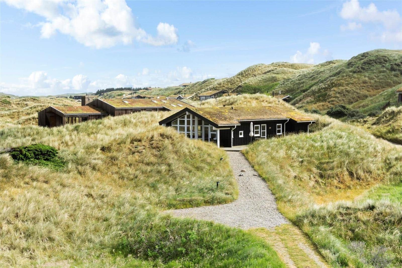 Haus mit grasbedecktem Dach in Dünenlandschaft