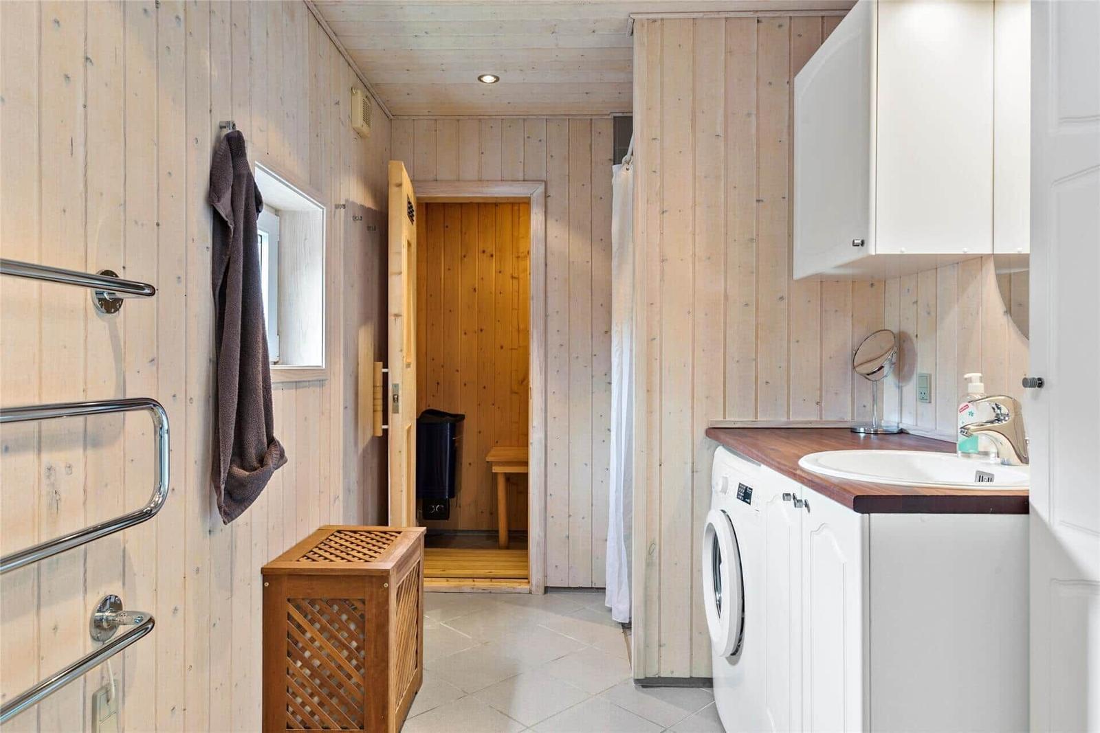 Badezimmer mit Sauna, Waschmaschine und Spiegelschrank.