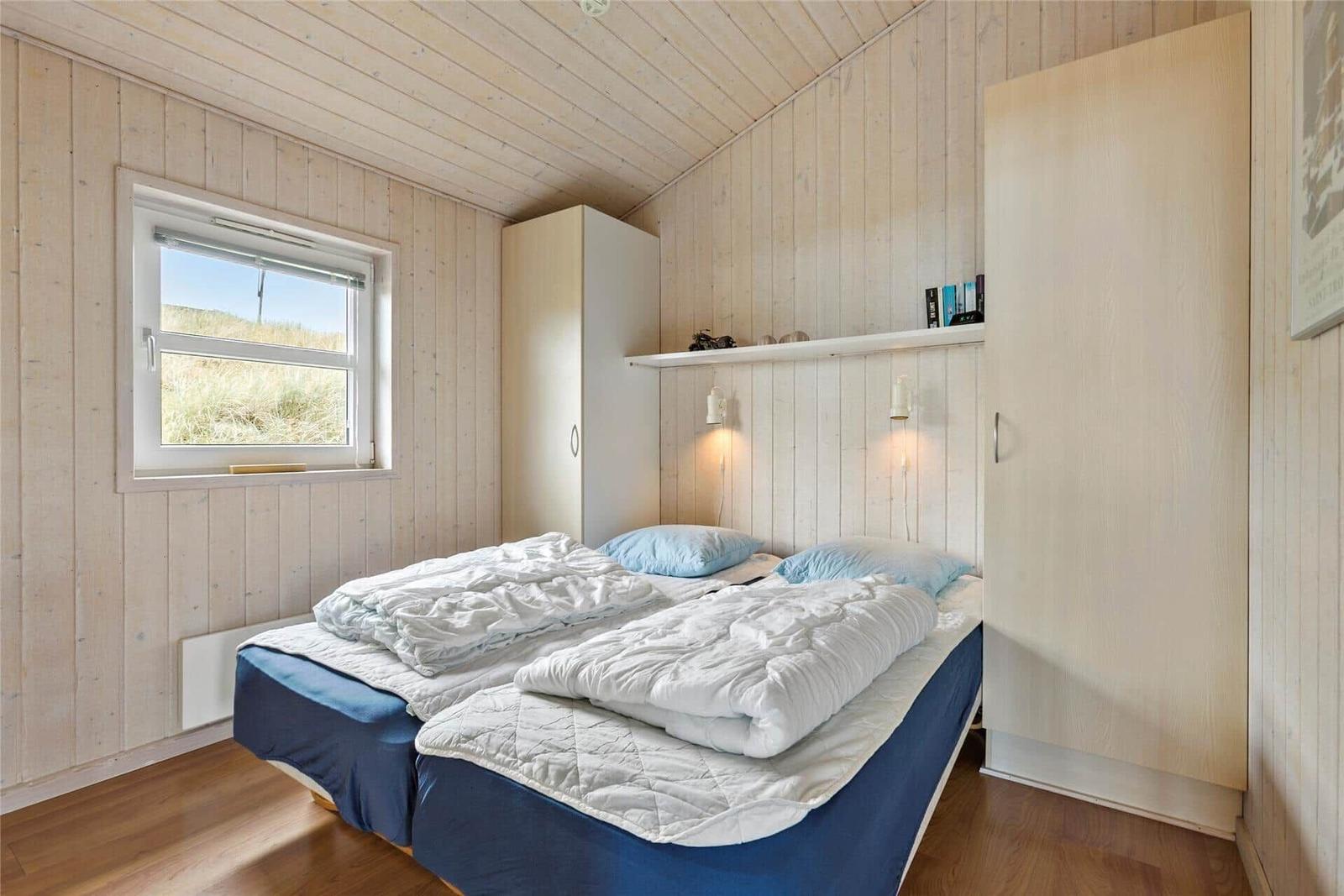 Schlafzimmer mit Doppelbett, Fenster und Schränken.