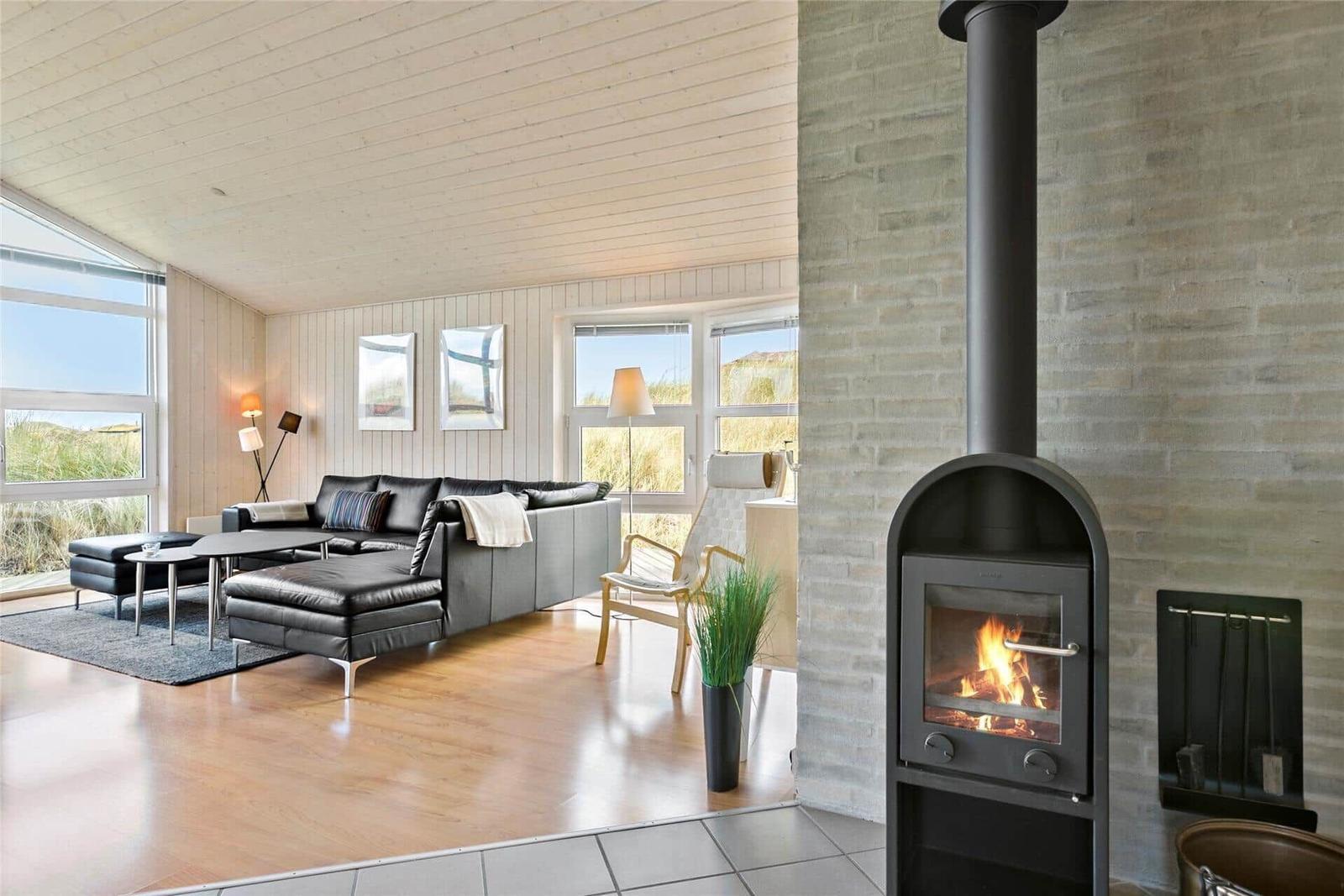 Wohnzimmer mit Kamin, Sofa und Blick auf die Landschaft.