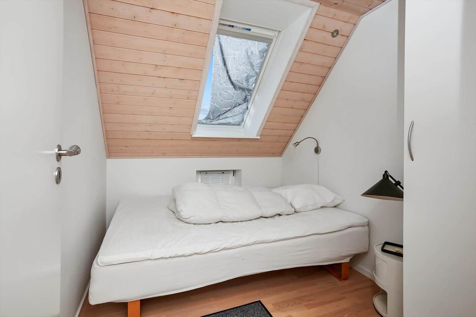 Dachgeschosszimmer mit Doppelbett, Holzdecke und Dachfenster.