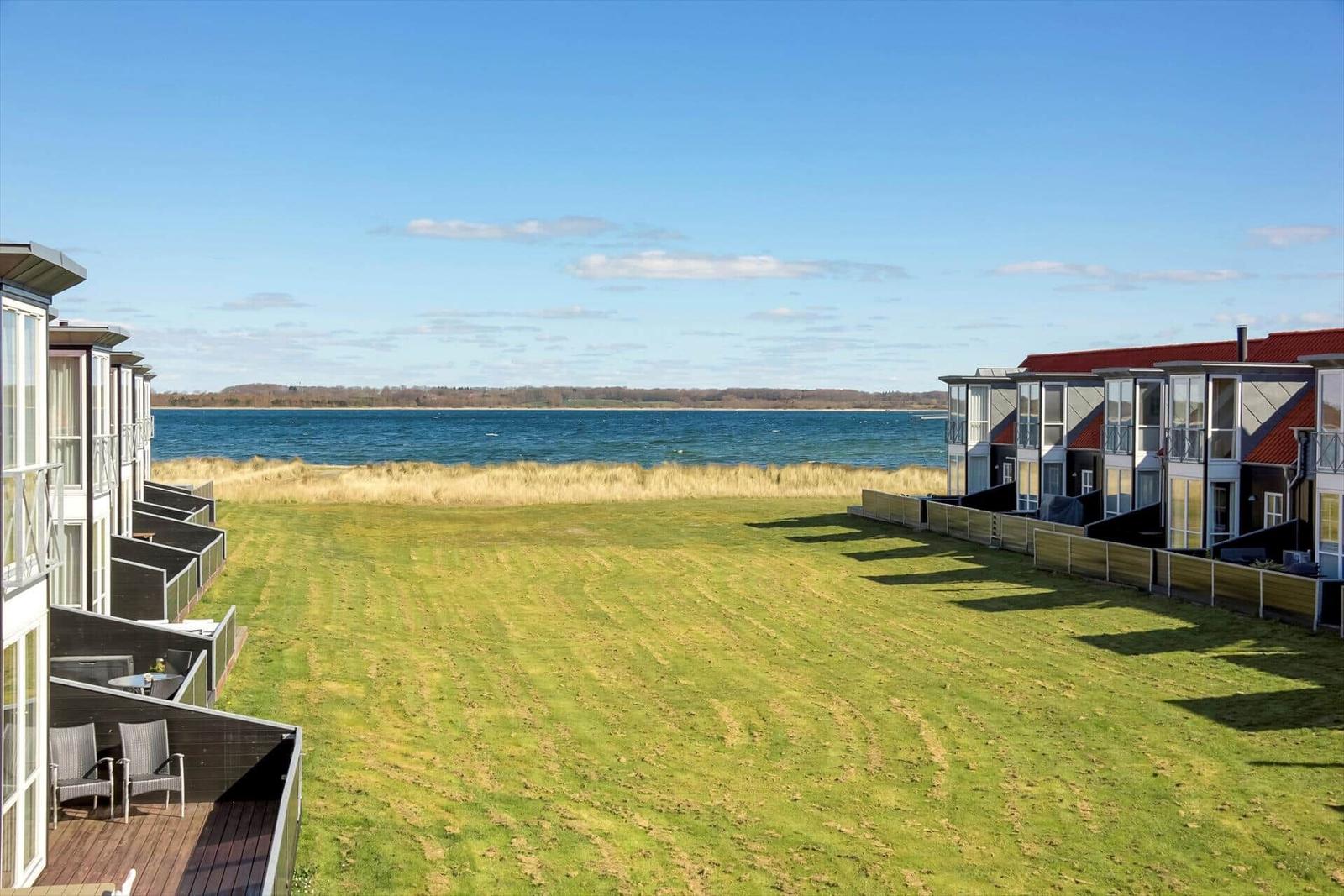 Grüner Rasenbereich mit Blick auf Wasser und Ferienhäuser.