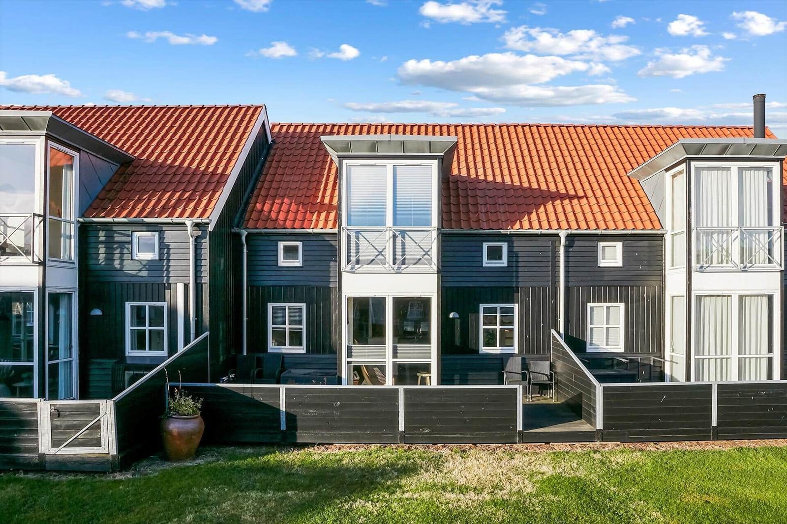 Moderne Ferienwohnung mit rotem Dach und Balkonen im Freien.