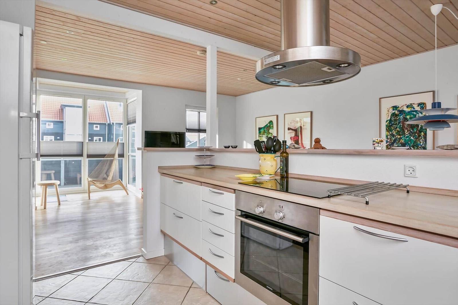 Küche mit Holzoberflächen und Blick auf Balkon mit Hängesessel.