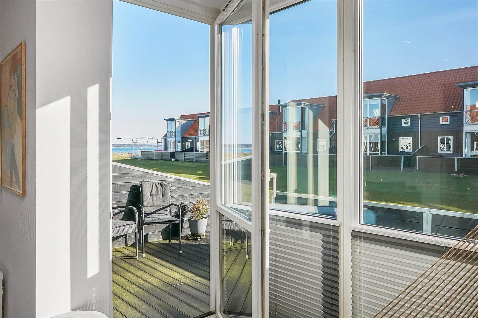 Terrasse mit Sitzgelegenheit und Blick auf Wohnhäuser und Wasser.