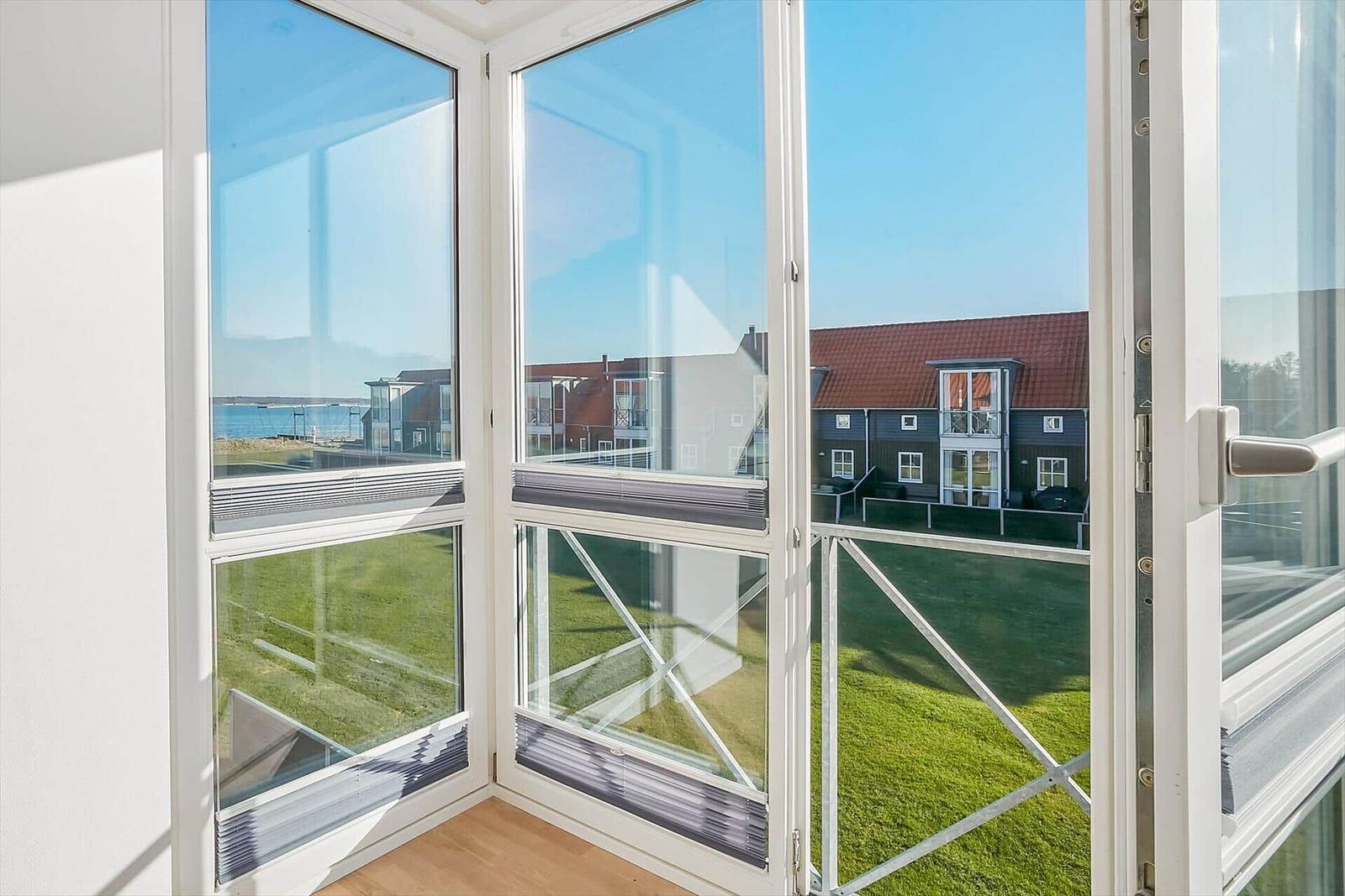 Durch große Fenster mit Blick auf Grünfläche und Häuser.