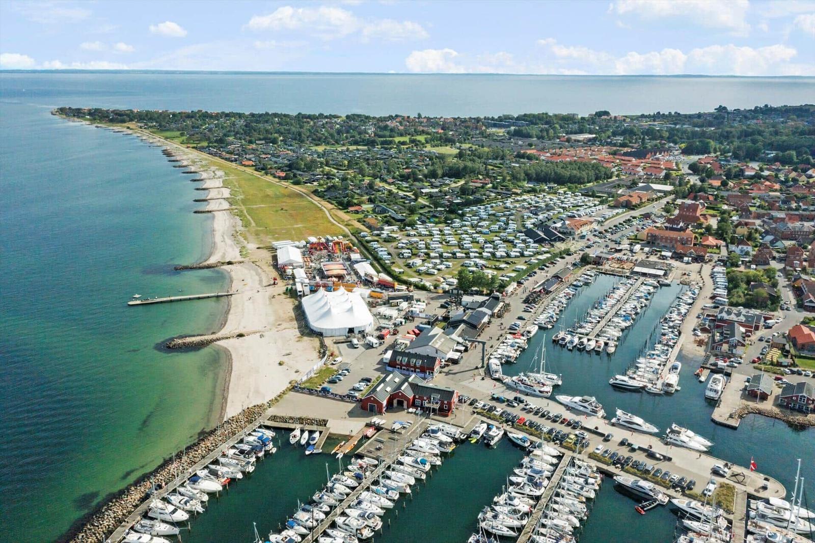 Hafen mit Booten, Strand und Ferienpark in der Ferne.