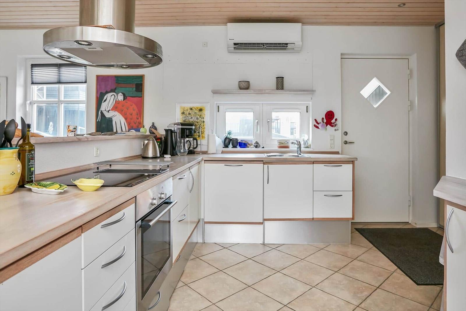 Küche mit weißen Schränken, Holzoberflächen und Edelstahlgeräten.