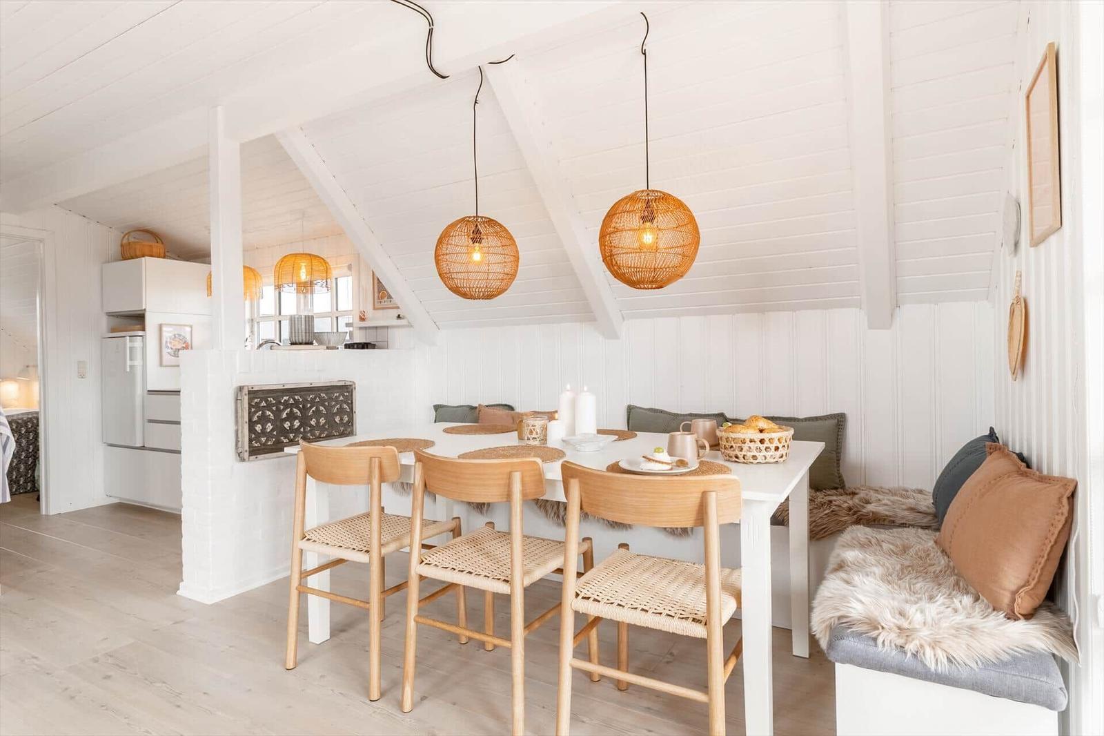 Essbereich mit Tisch, Stühlen und Sitzbank unter weißem Dach.