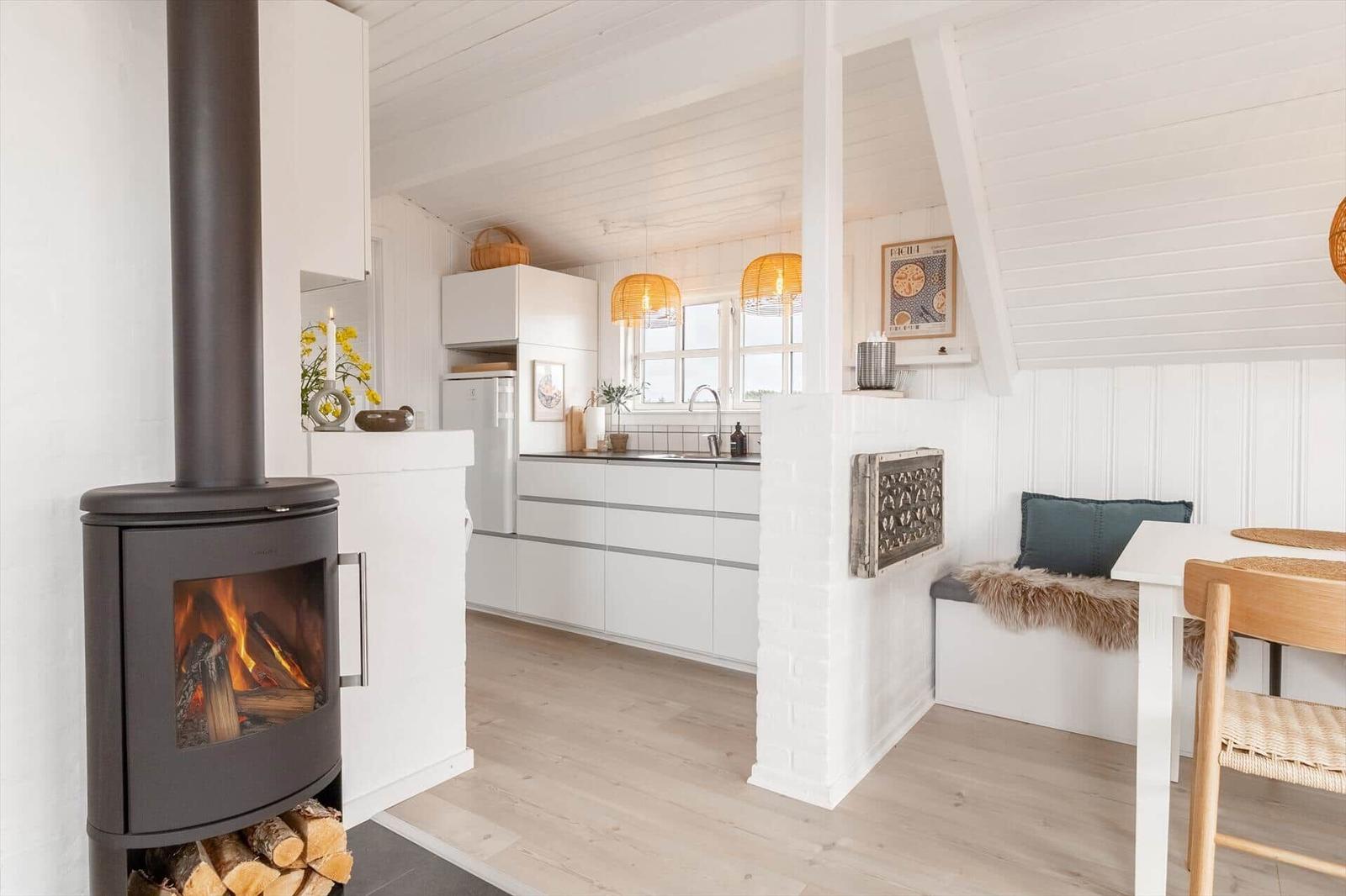Küche mit Essbereich und Kaminofen. Weiße Einbauküche und Sitzbank mit Felldecke.