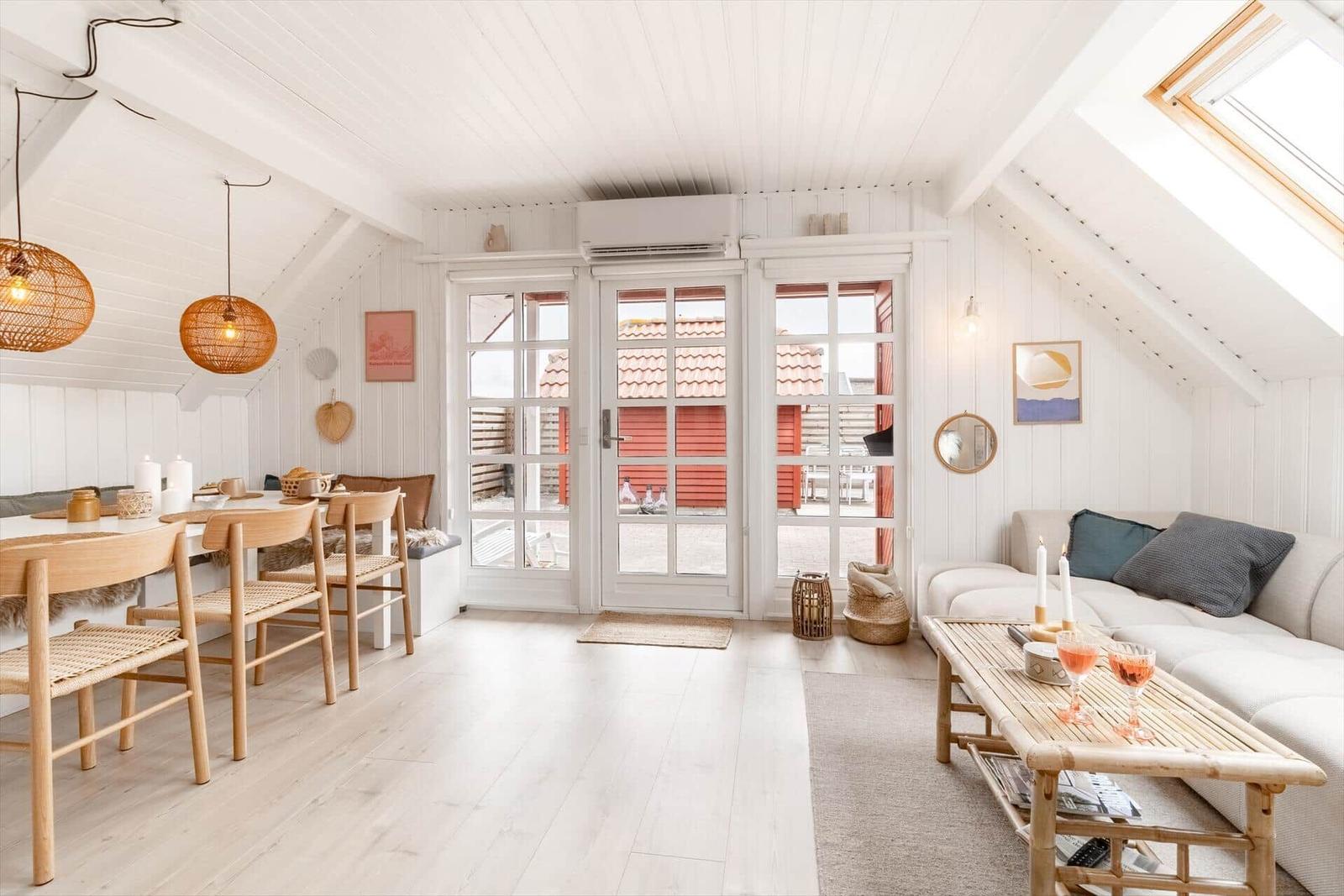 Wohn- und Essbereich mit weißen Wänden, Holzboden und französischen Türen.