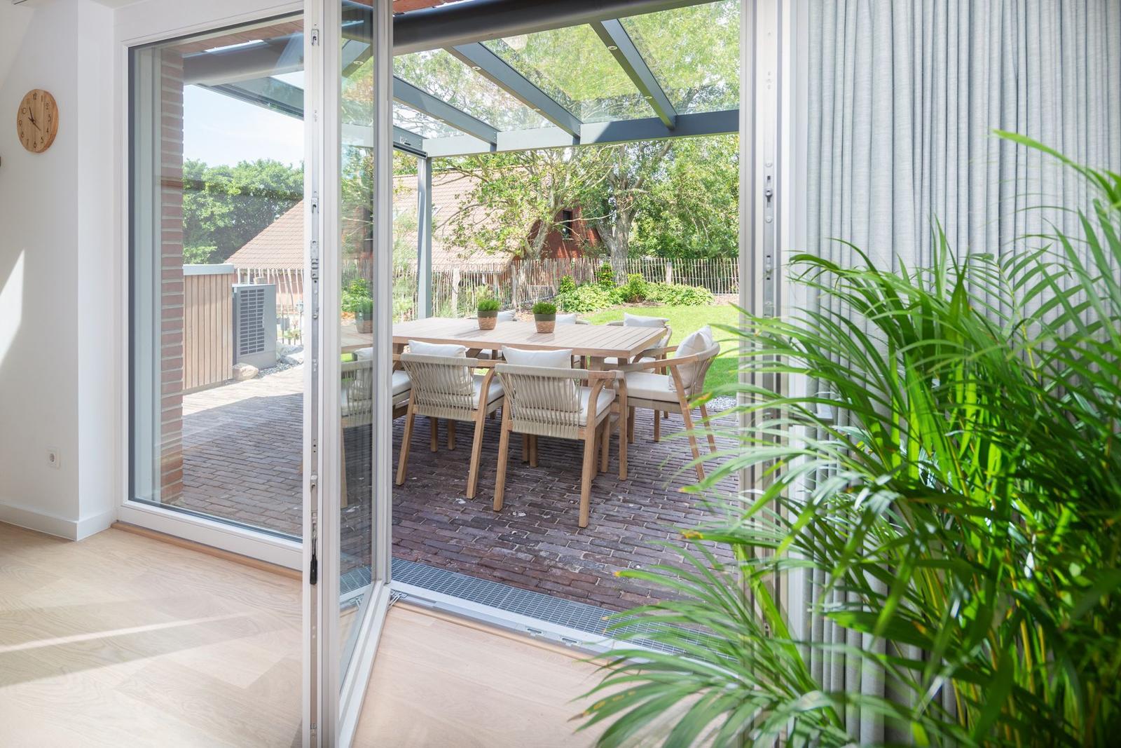 Glas-Tür führt auf Terrasse mit Tisch und Stühlen.