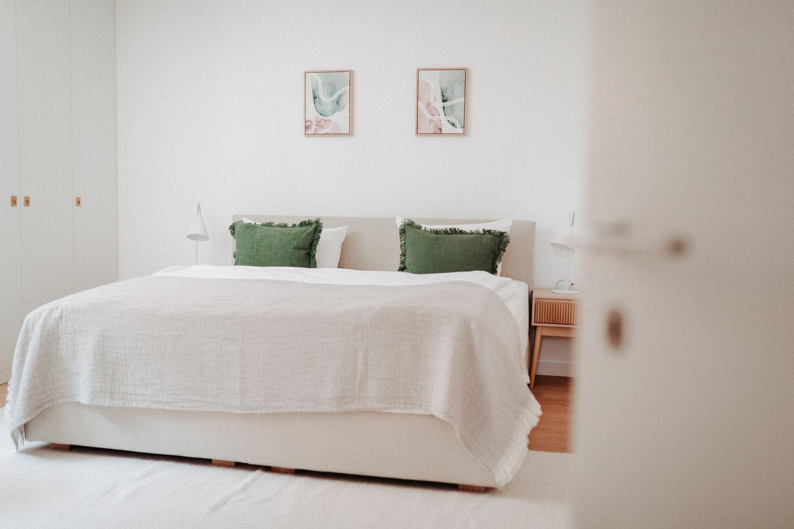 Schlafzimmer mit Bett, zwei Nachttischen und Wandbildern.