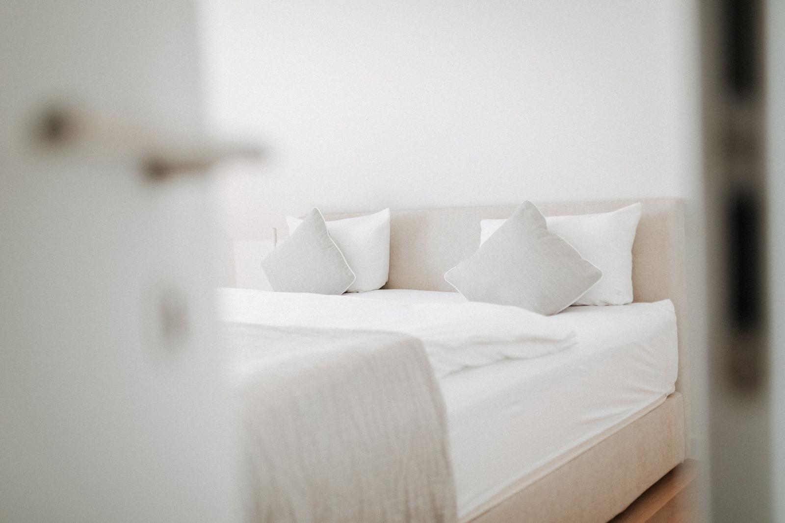 Ein Bett mit weißen Kissen und Bettwäsche im Schlafzimmer.