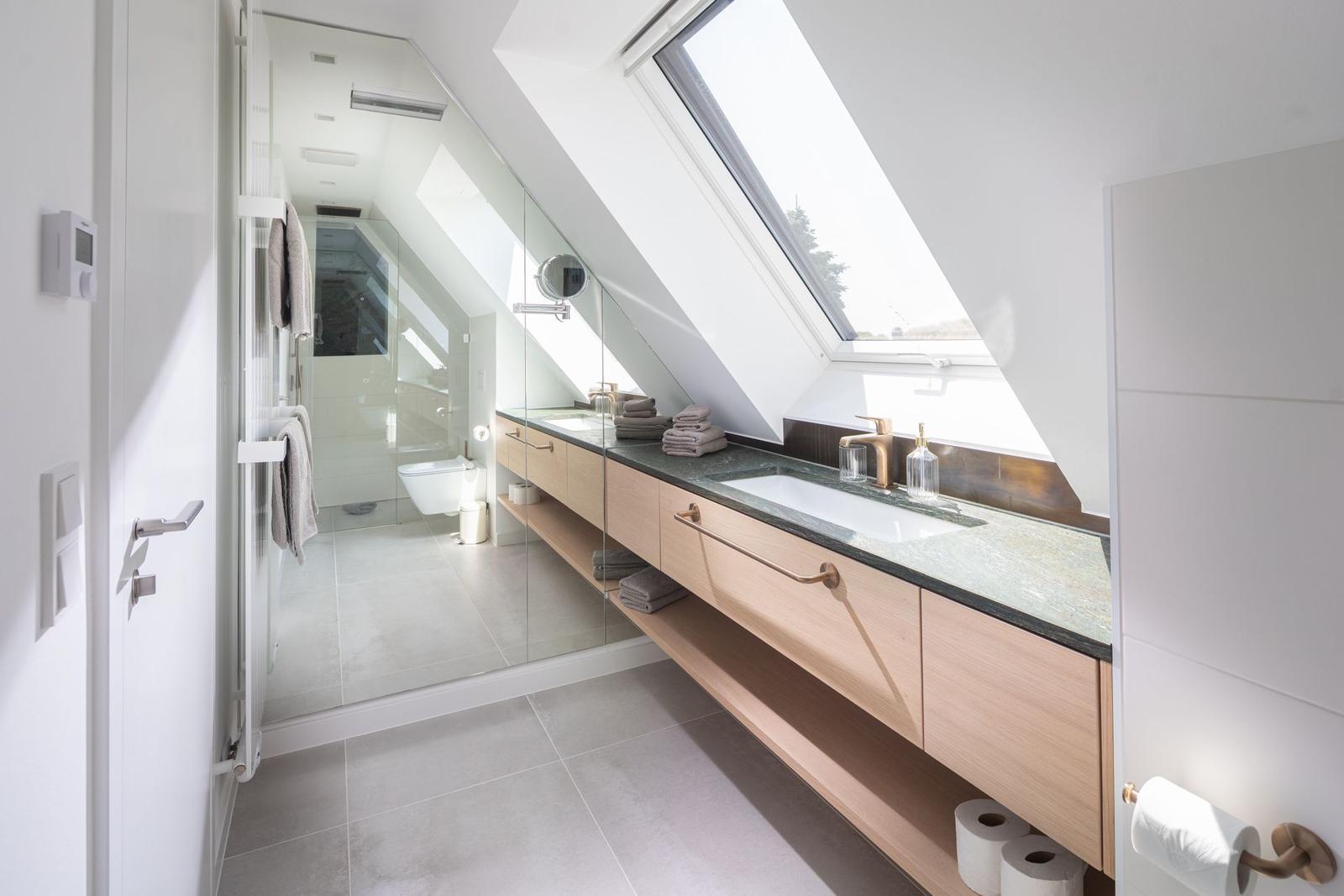 Badezimmer mit Dachschrägen, Waschbecken und Glaswand-Dusche.
