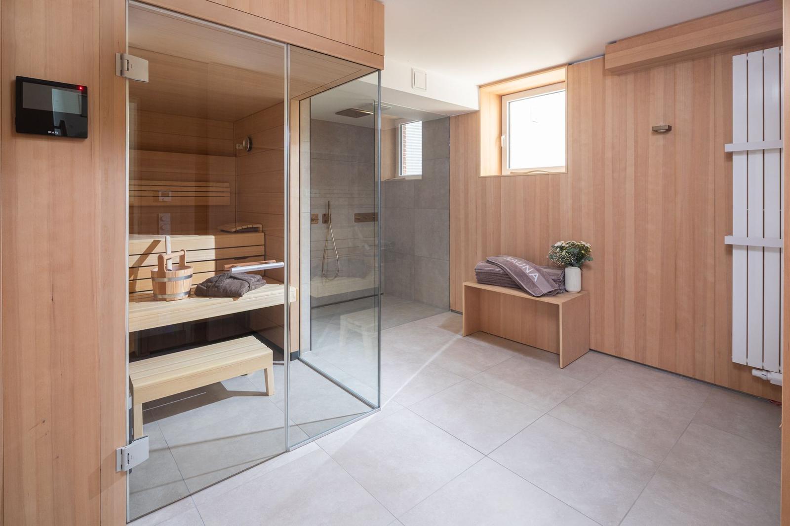 Dusche und Sauna in einem Raum mit Holzwänden und Bodenfliesen.
