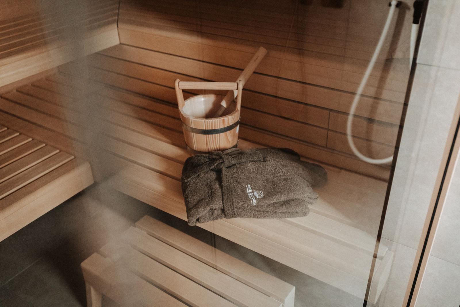 Sauna mit Holzbank, Eimer und Handtuch.