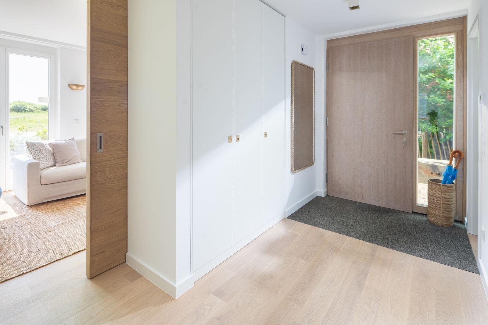 Eingangsbereich mit Schuhschrank, Tür und Blick in Wohnzimmer.