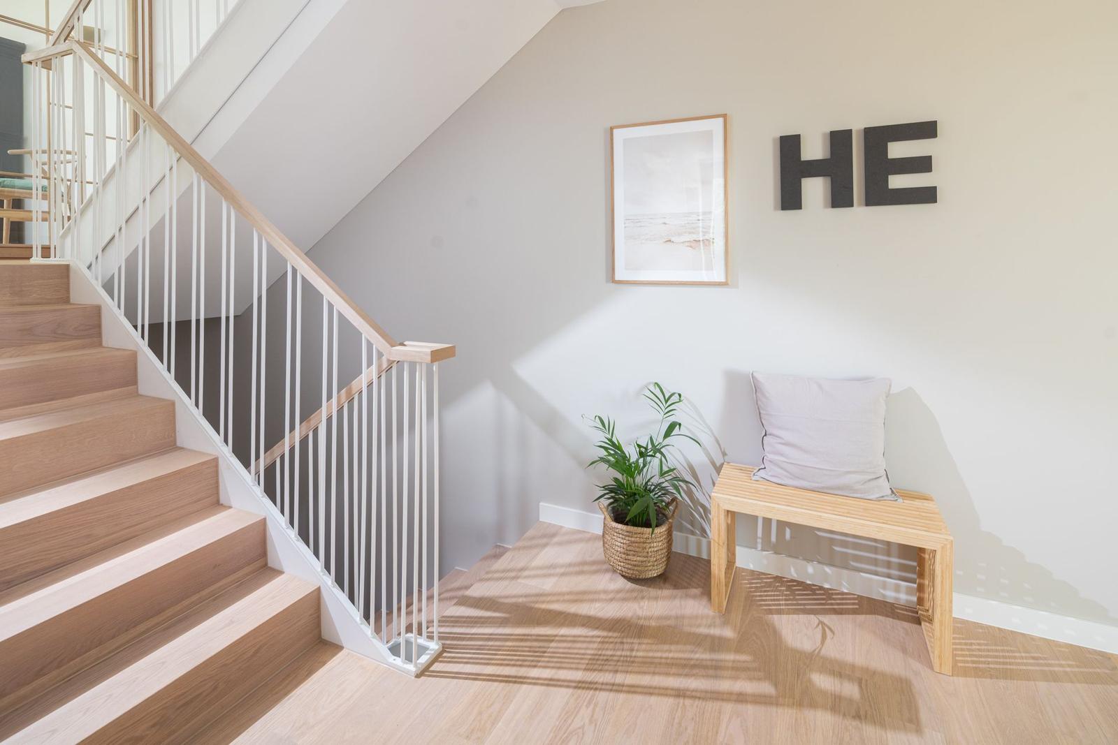 Treppenhaus mit Holzstufen, Sitzbank und Pflanze an der Wand.