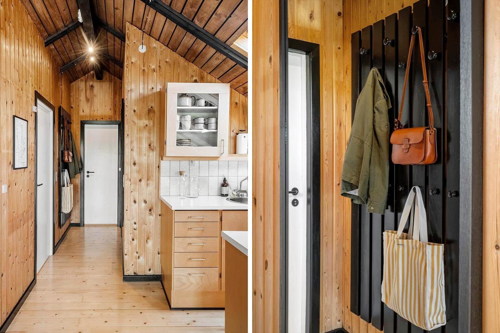 Holzgetäfeltes Interieur mit Küche und Garderobe. Helle Arbeitsfläche und schwarze Metallstangen.