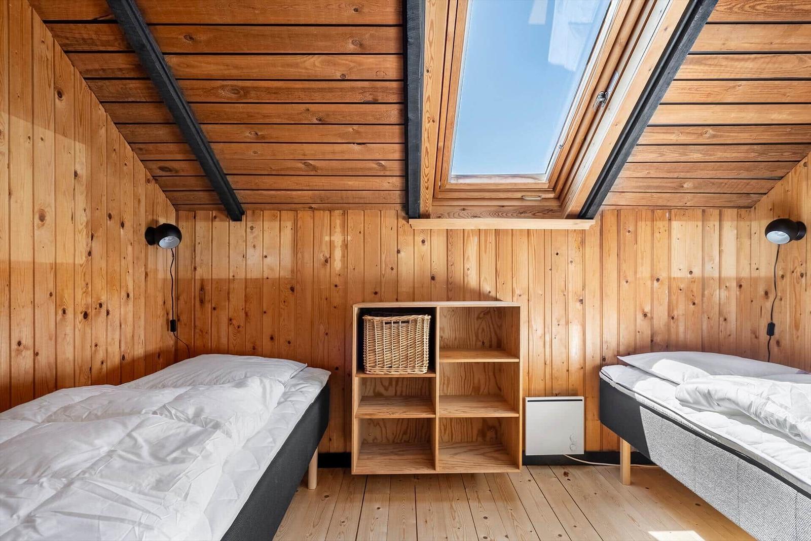 Zwei Betten unter Holzdach mit Dachfenster und Regal.