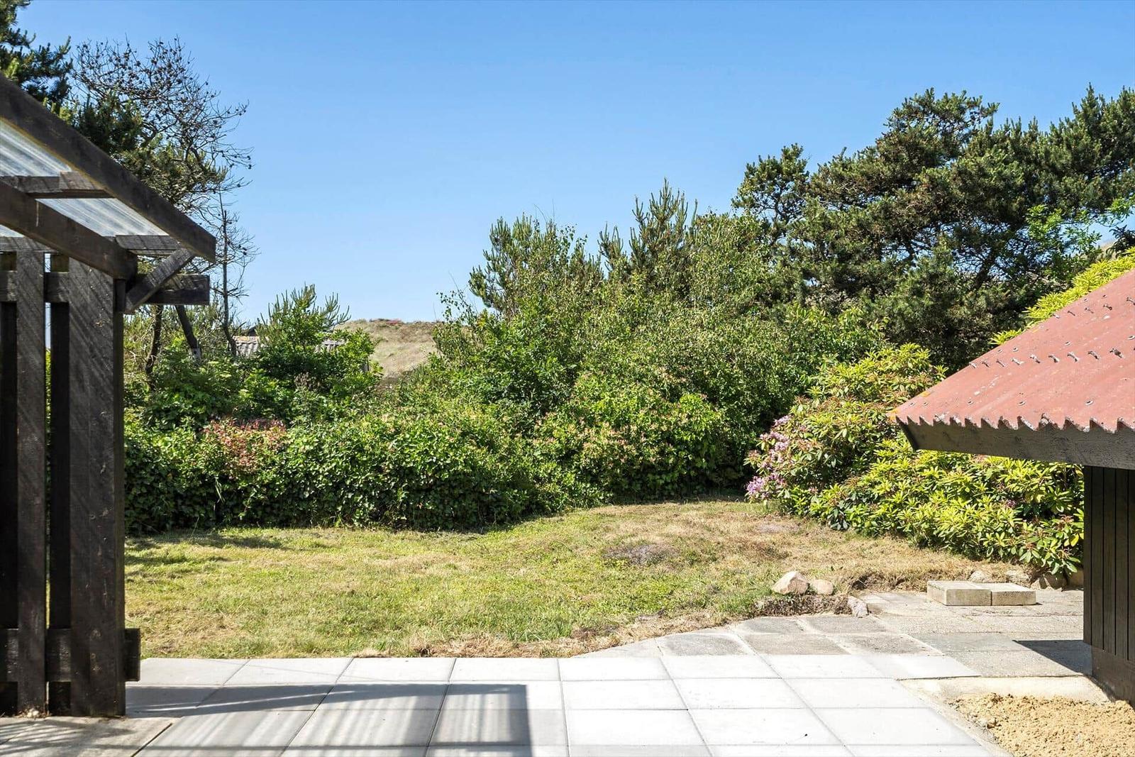 Garten mit Grasfläche, Bäumen und Steinweg vor Holzgebäude.
