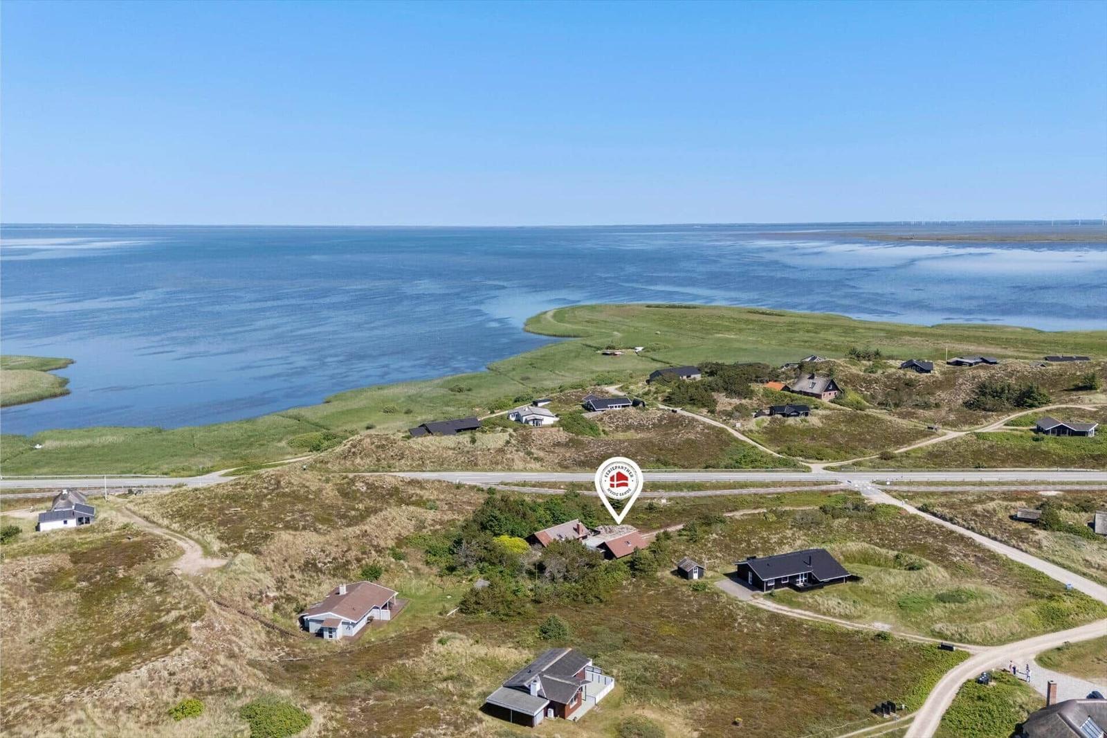 Aerial view of coastal property with houses on grassy terrain near water.