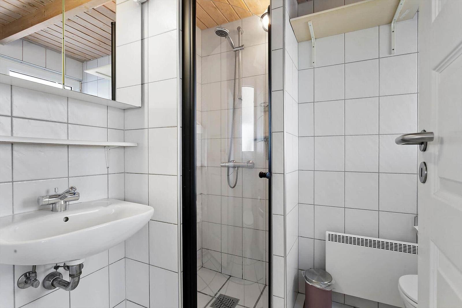 Badezimmer mit Dusche, Waschbecken und Toilette.