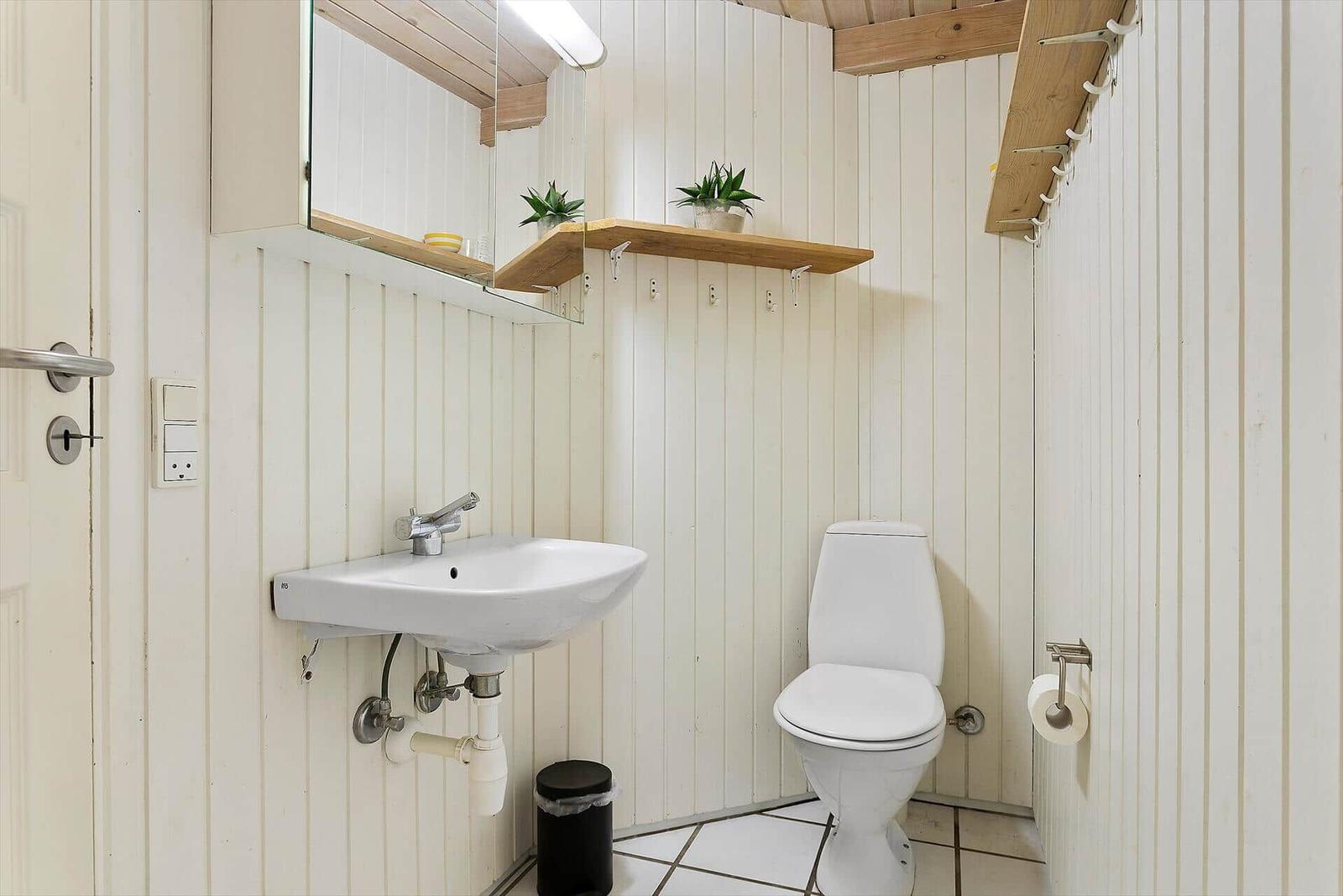 Badezimmer mit Toilette, Waschbecken und Spiegel an der Wand.