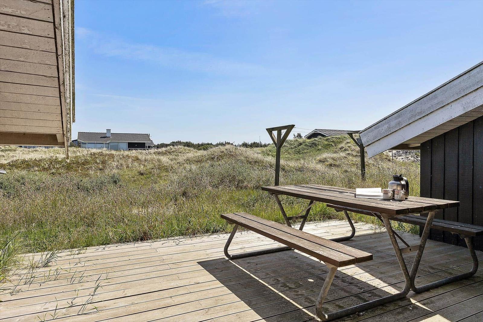 Holzterrasse mit Picknicktisch und Blick auf Dünen
