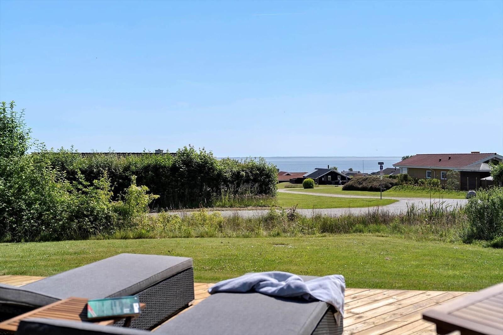Deck with loungers and view of lawn and sea.
