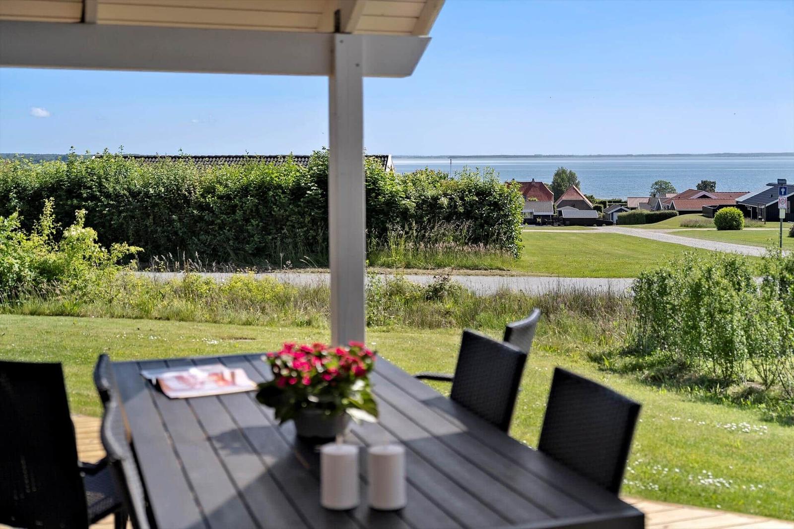Patio with table and chairs, view of green lawn and lake.