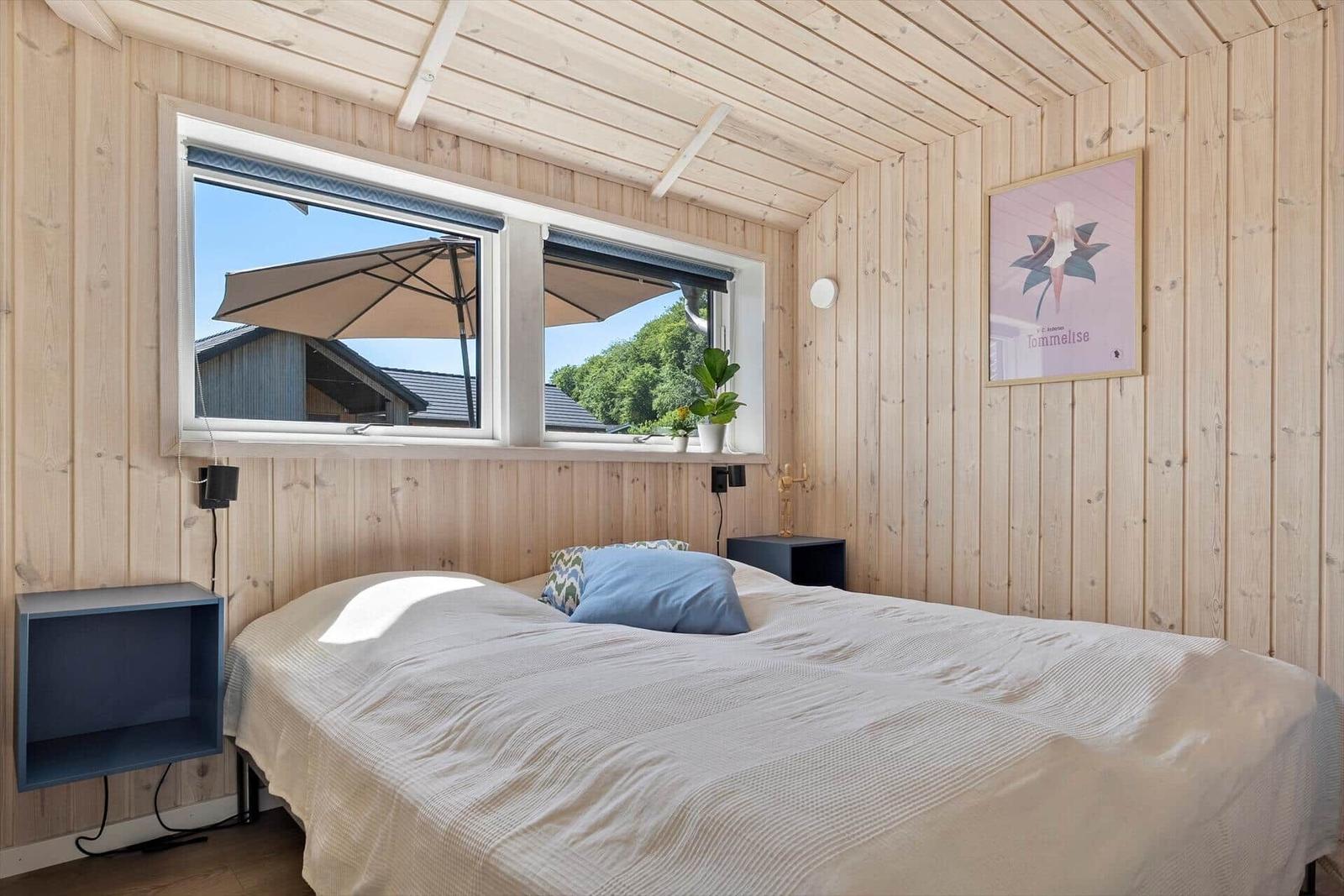 Bedroom with wooden walls, bed, window, and wall art.