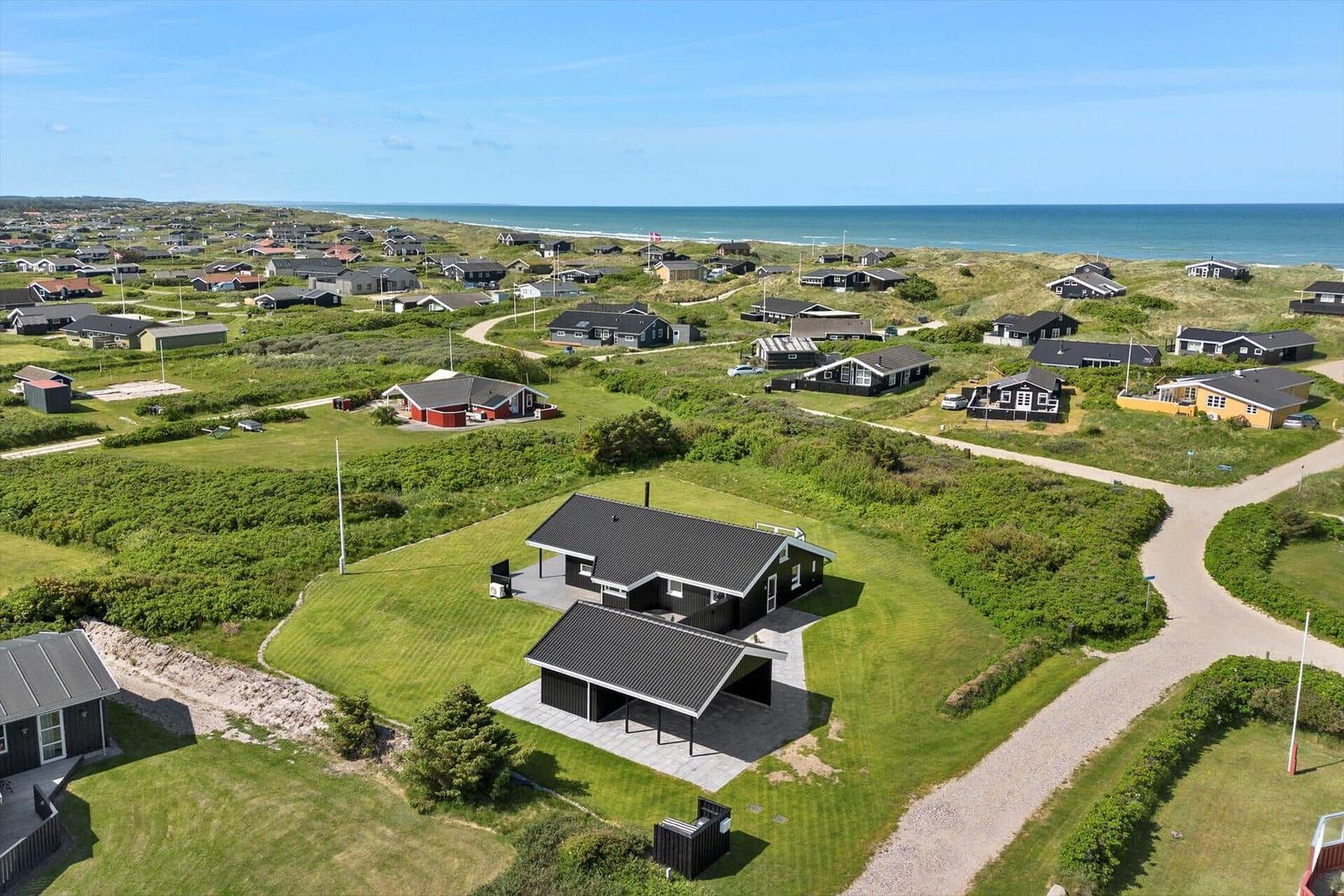 Schwarzes Haus mit Terrasse auf grünem Grundstück nahe Strand