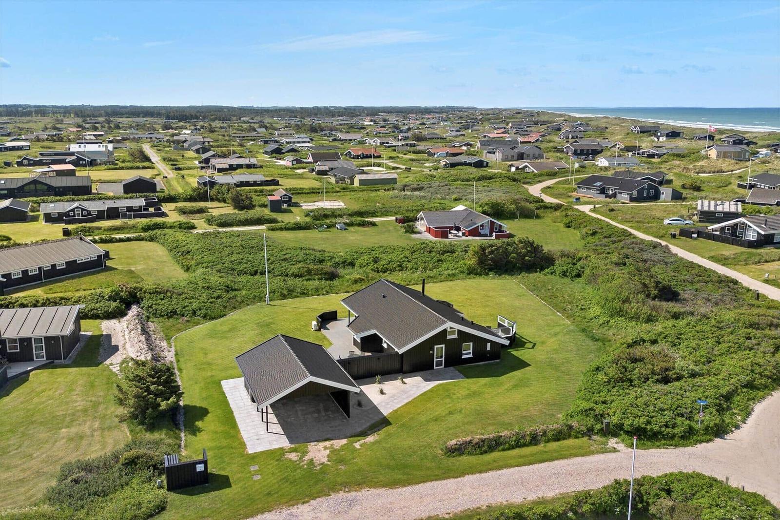 Haus mit Garage auf grünem Grundstück, Blick auf Strand und Dorf.