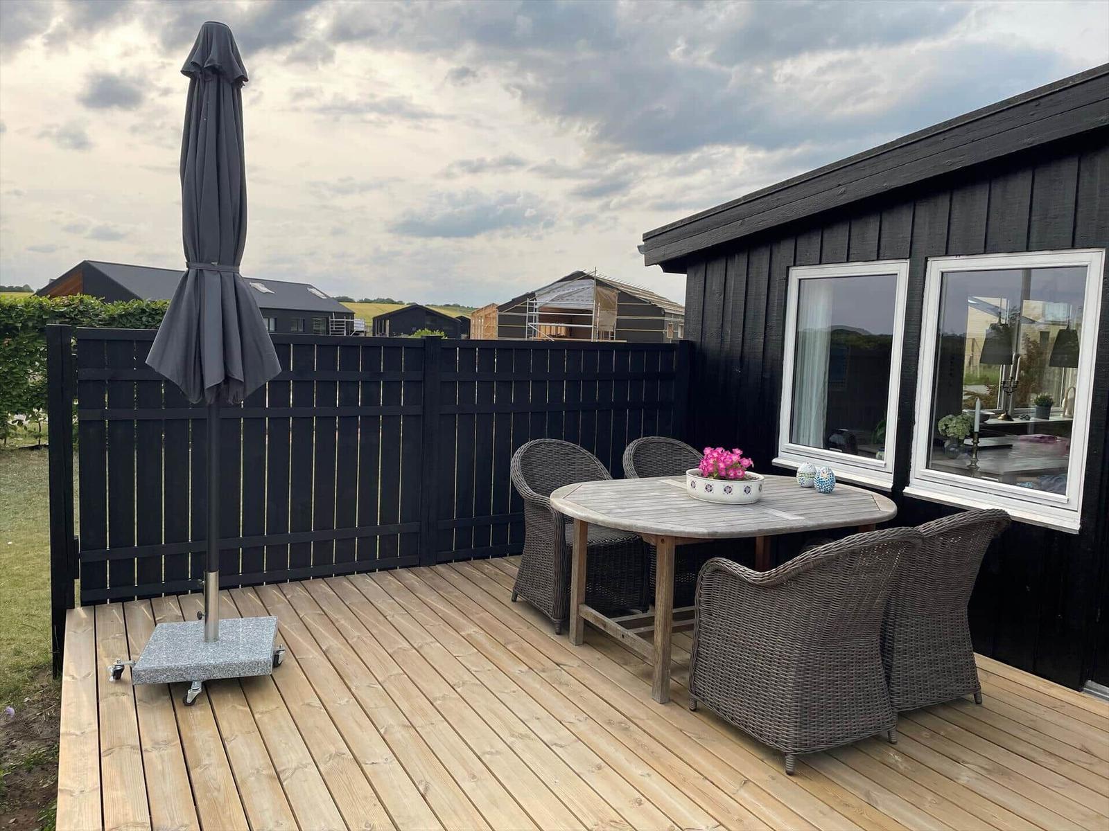 Terrasse mit Tisch, Stühlen und Sonnenschirm neben einem Haus