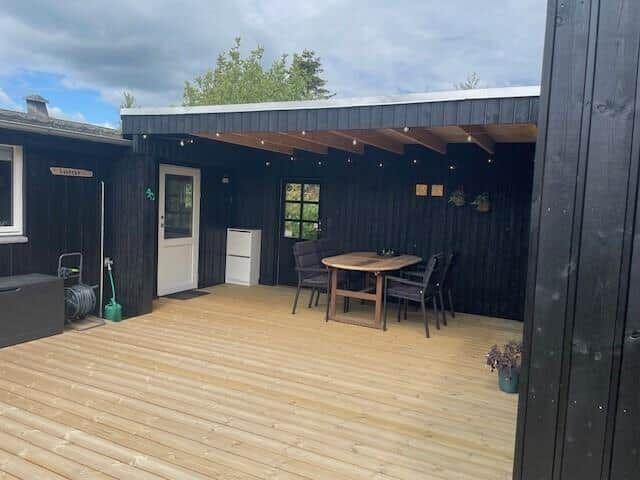 Terrasse mit Tisch, Stühlen und Beleuchtung unter Dach