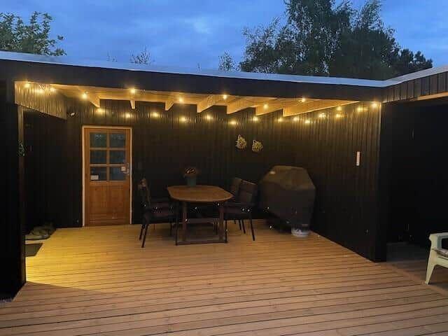 Terrasse mit Tisch, Stühlen und Grill unter Lichterkette
