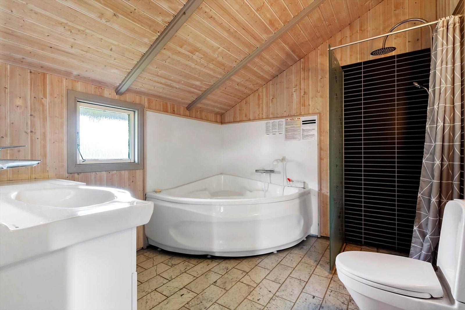 Bathroom with bathtub, shower, and sink. Wooden walls and ceiling.