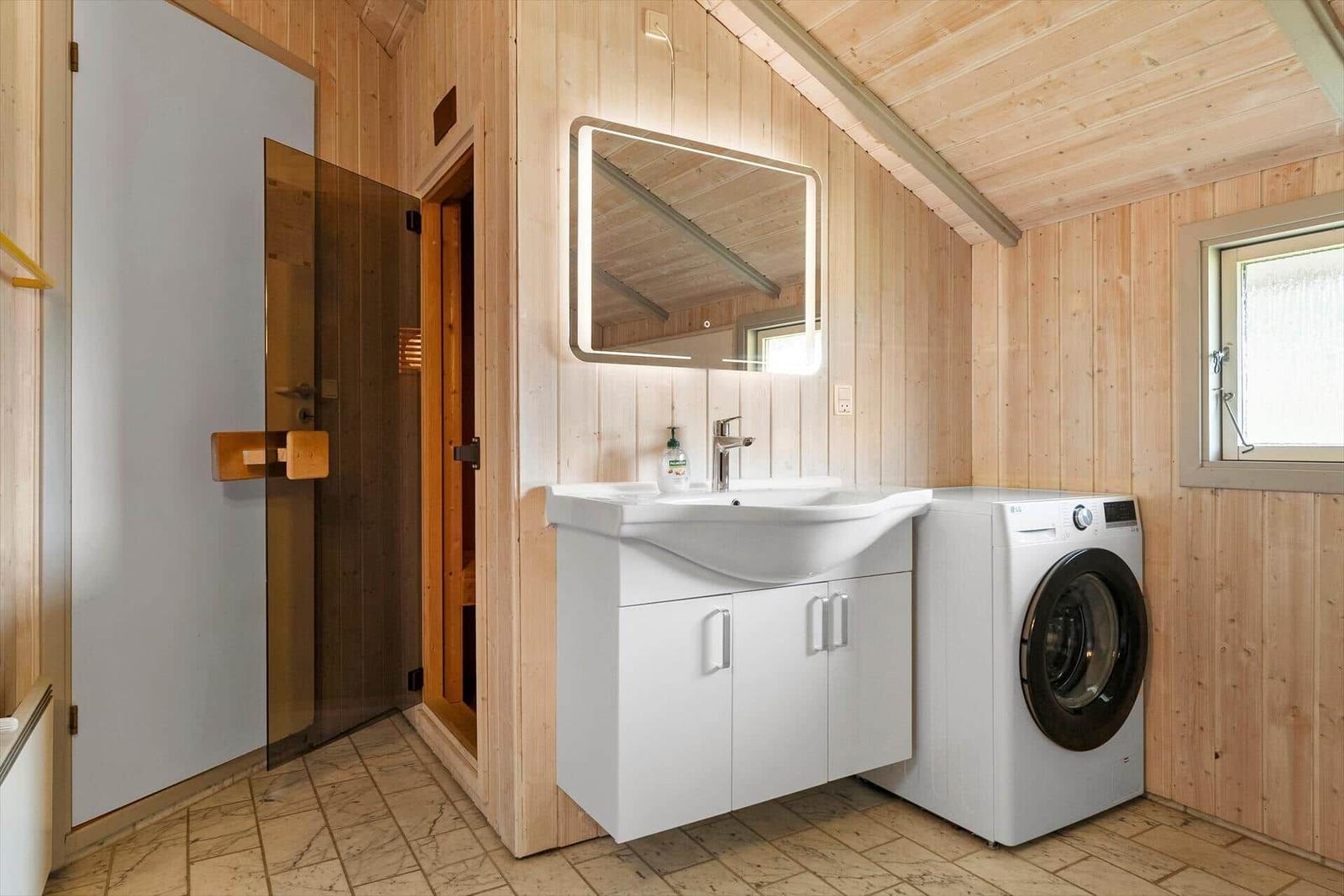 Bathroom with washing machine and mirror cabinet in wooden house.