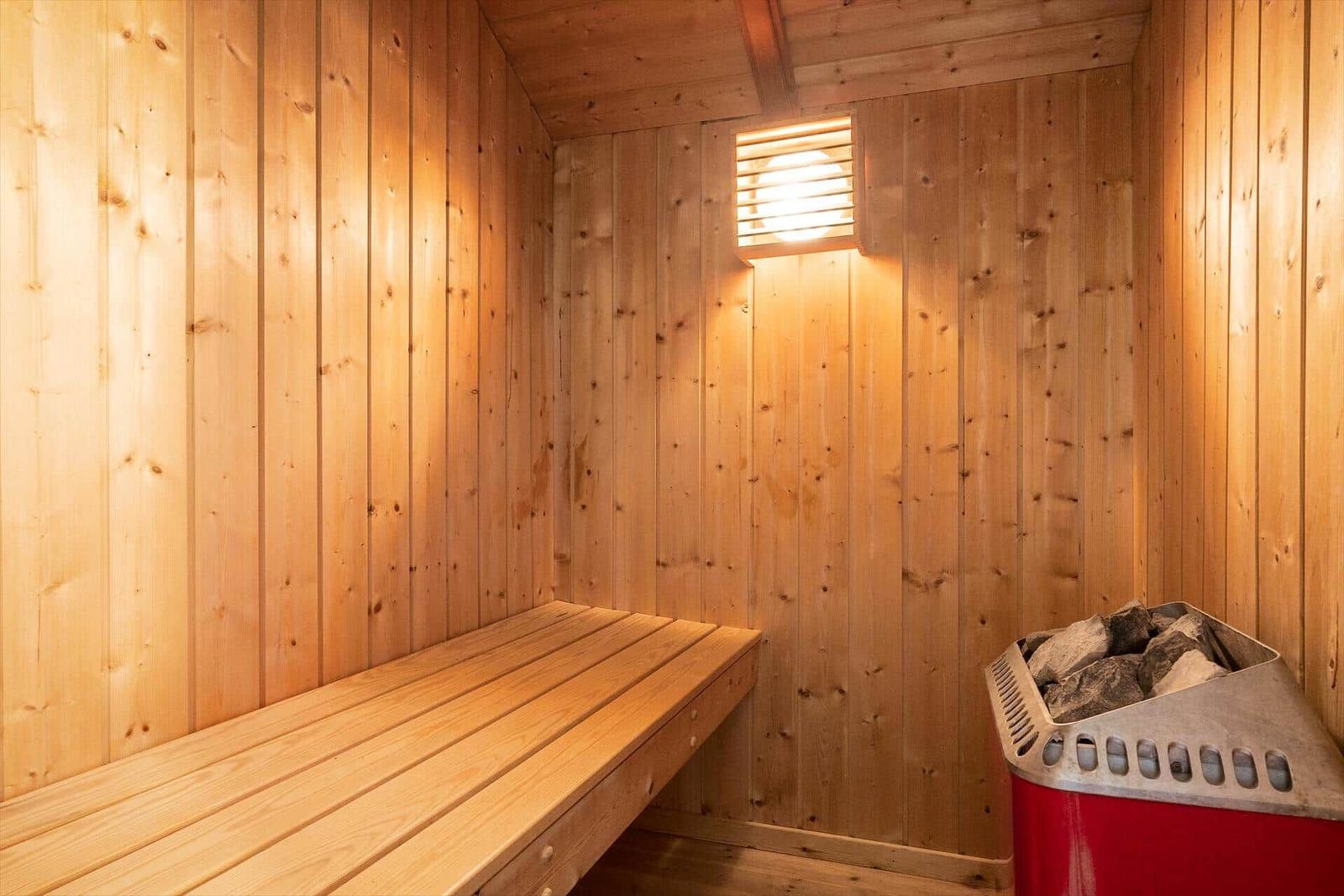 Sauna with wooden walls, bench, and stone basket