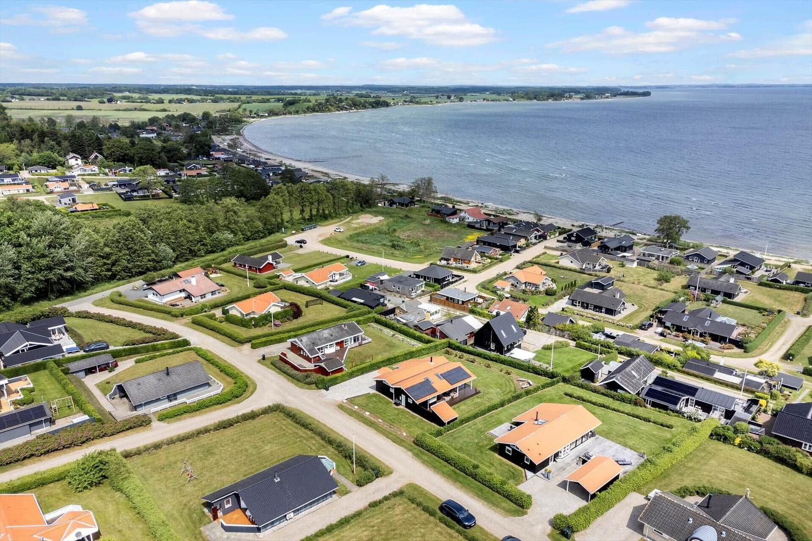 Aerial view of houses by the lake with green areas and paths.