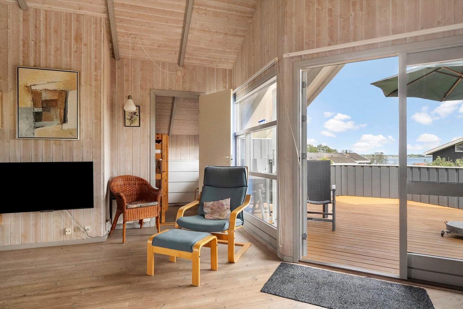 Living room with wood walls, chair, and view of terrace.