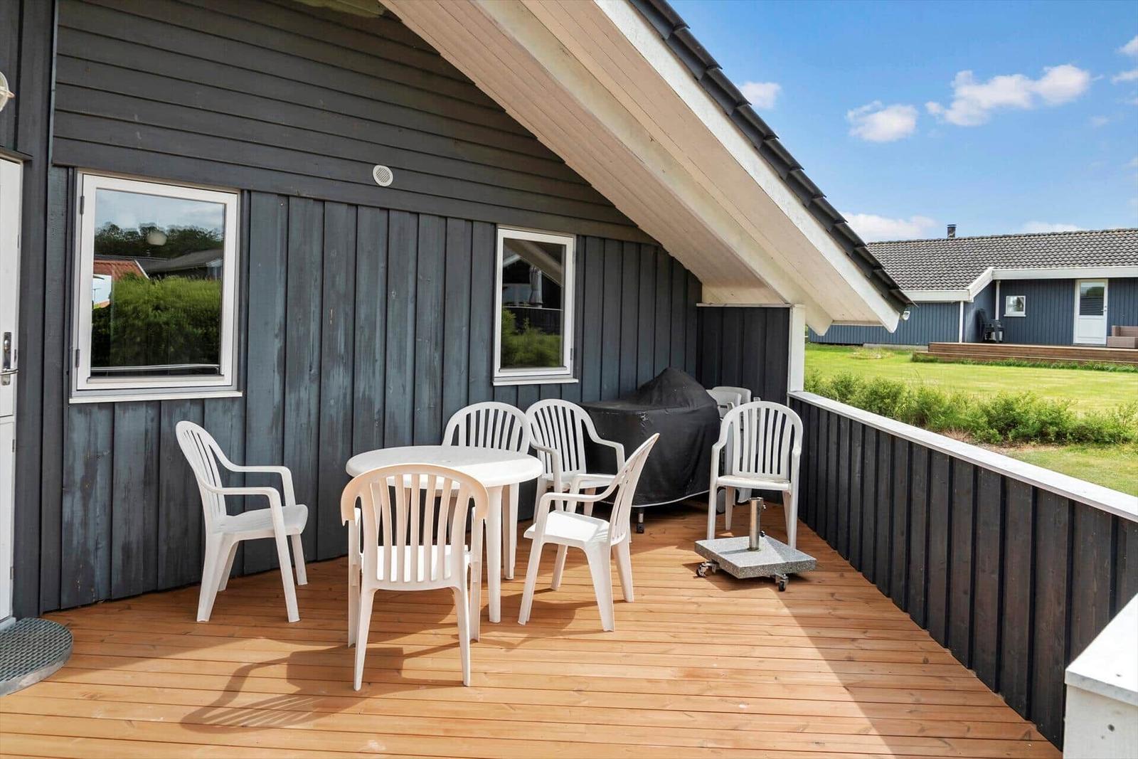 Deck with white table and chairs, grill, and wooden floor.
