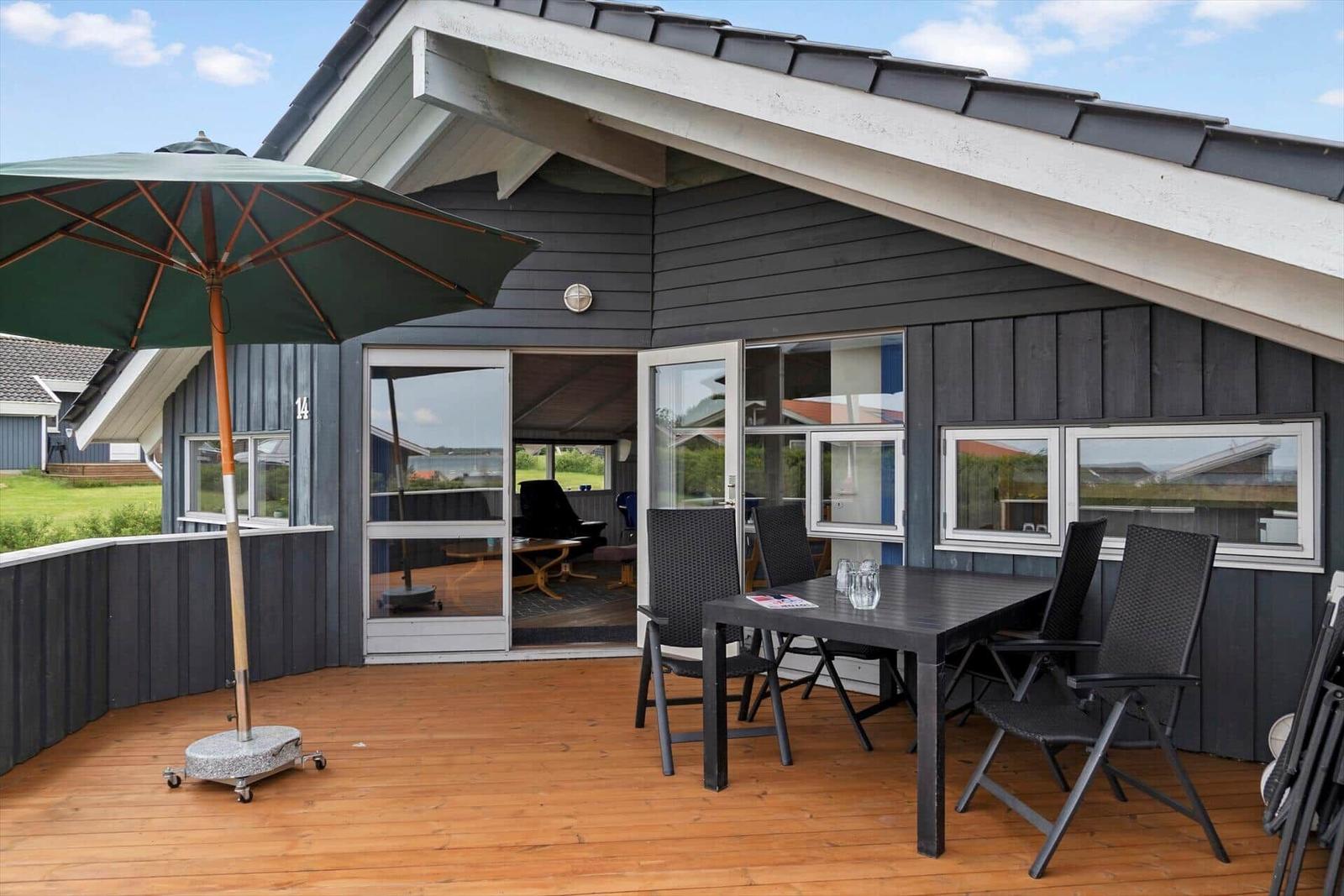 Terrace with table, chairs, and umbrella. Glass doors lead inside.