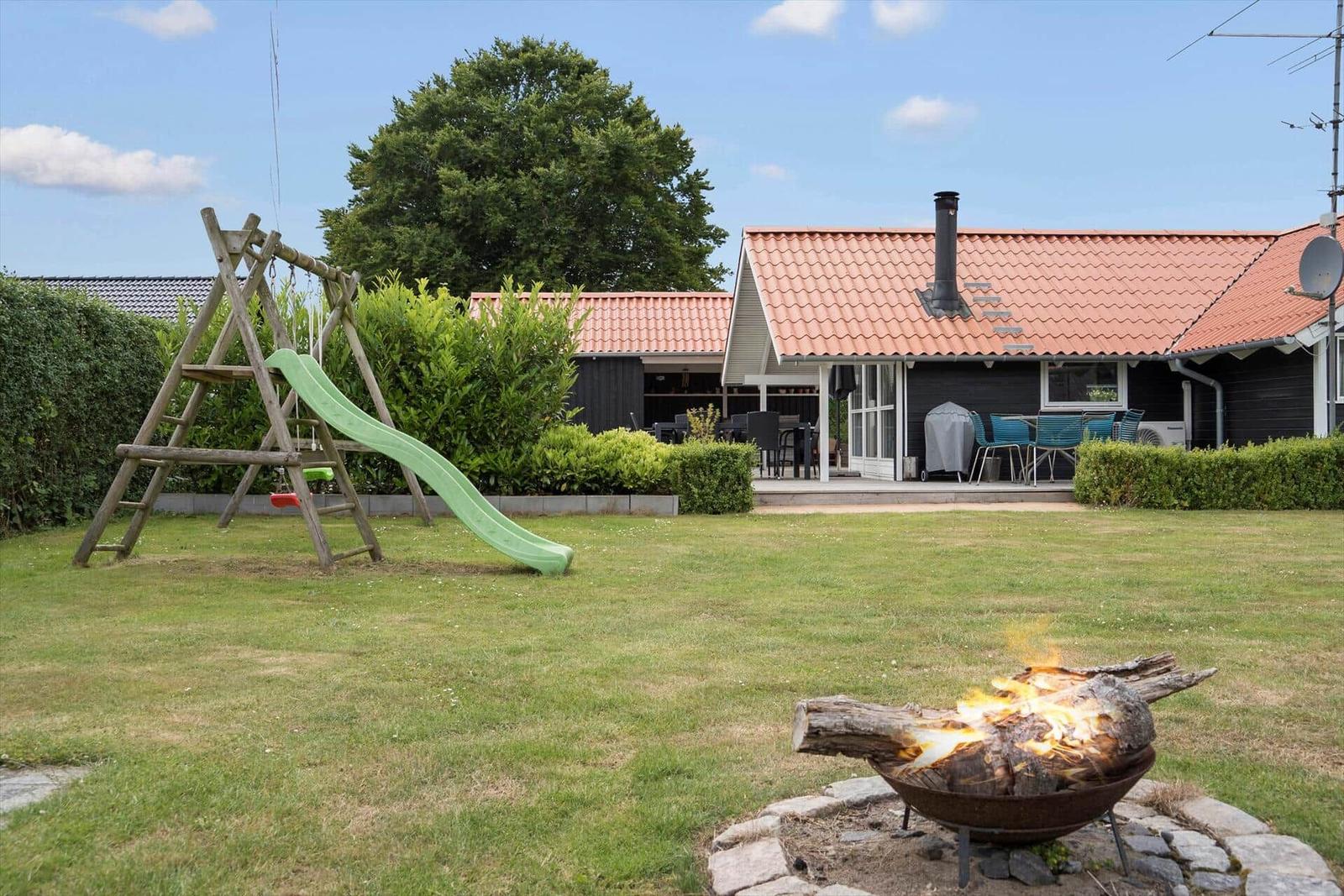 House with garden, playground, and burning fire pit.