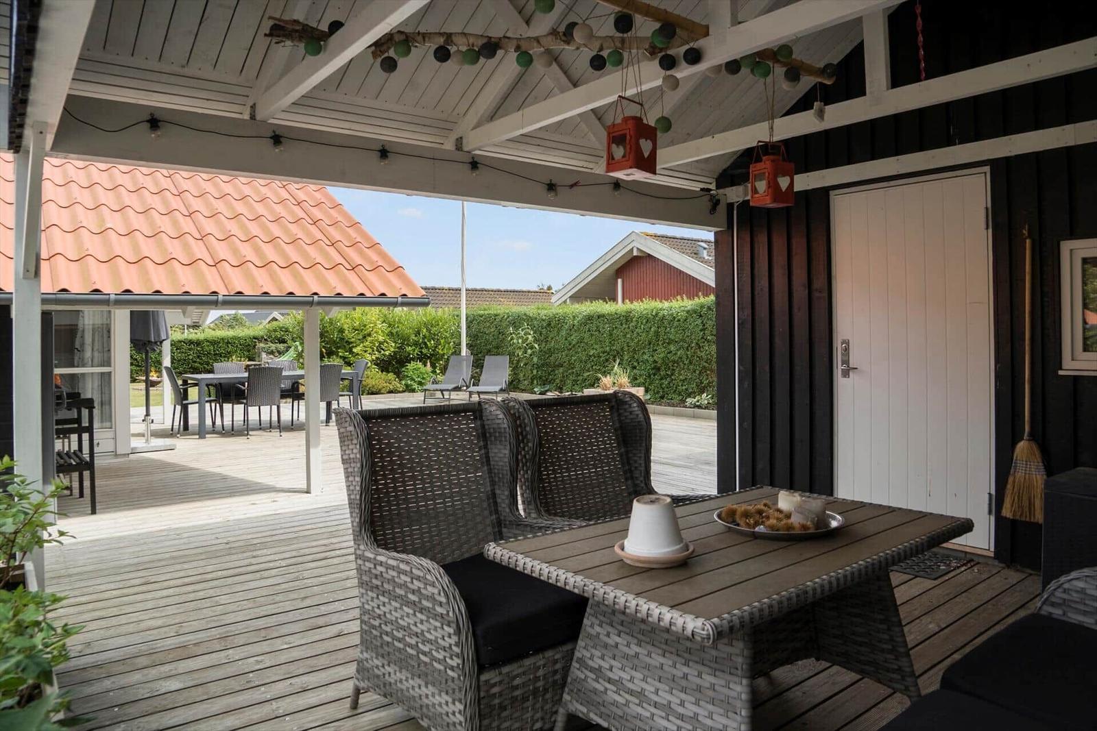 Patio with seating, table, and hanging lanterns under roof.