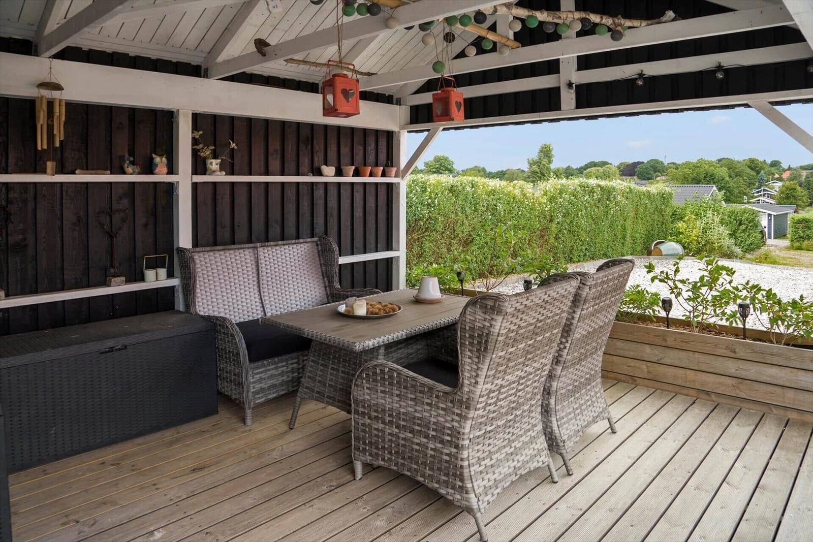 Terrace with seating group, table, and plants. Wooden deck and dark walls.