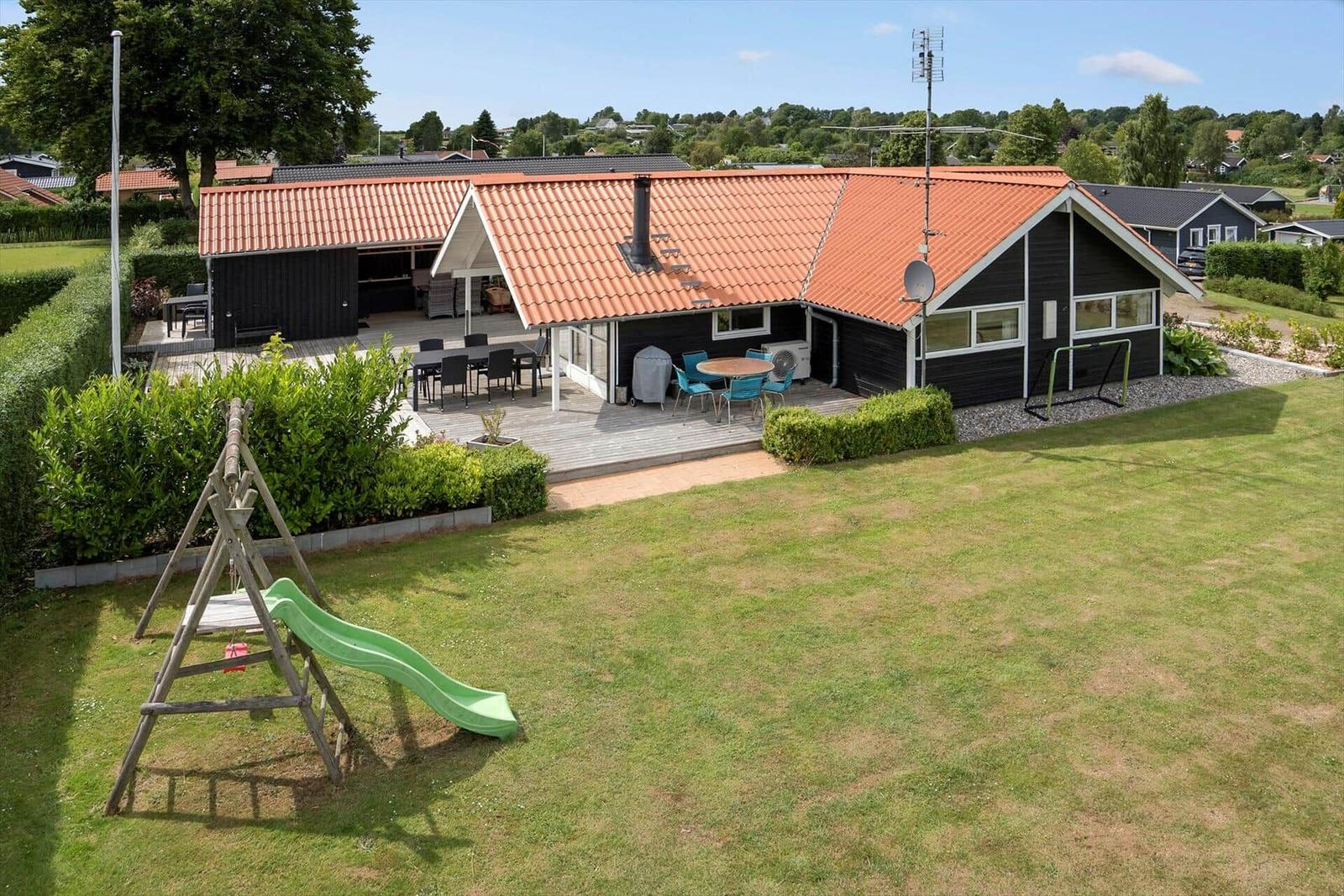House with terrace, barbecue area, and playground in the garden.